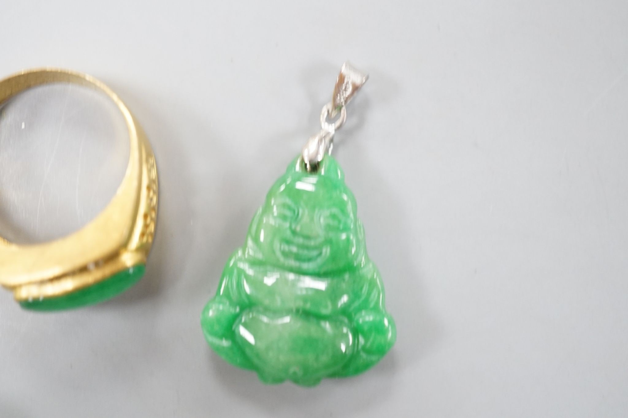 A carved jade pendant, 53mm on a quartz bead necklace, one other jade pendant and a jade, paste and gilt metal ring.